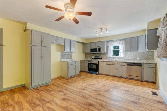 kitchen with light hardwood / wood-style floors, appliances with stainless steel finishes, ceiling fan, and tasteful backsplash