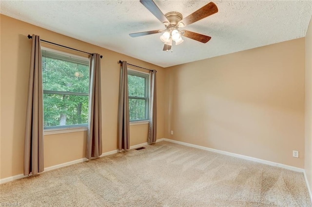 unfurnished room featuring ceiling fan, light colored carpet, and a textured ceiling