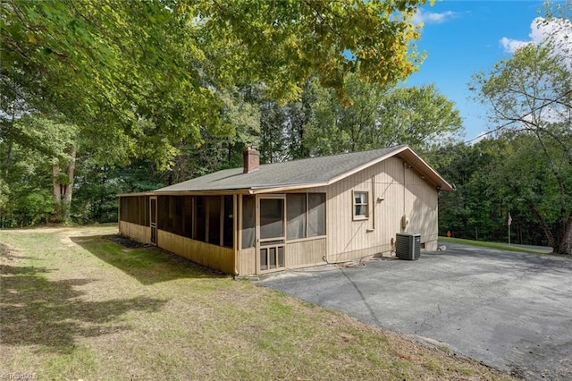 exterior space with a yard, a sunroom, and central air condition unit