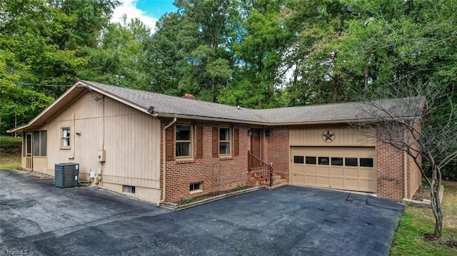 ranch-style home with central AC unit and a garage