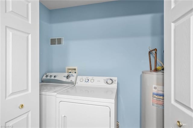 laundry area with visible vents, independent washer and dryer, water heater, and laundry area