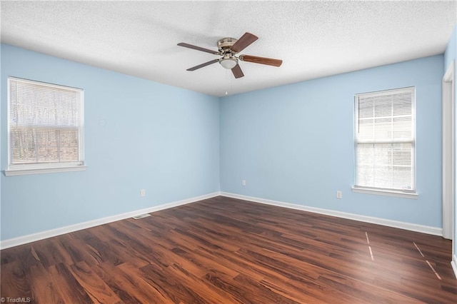 empty room featuring baseboards, a healthy amount of sunlight, and dark wood-style flooring