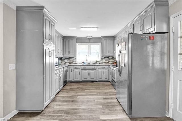 kitchen with gray cabinetry, sink, stainless steel appliances, tasteful backsplash, and light hardwood / wood-style flooring