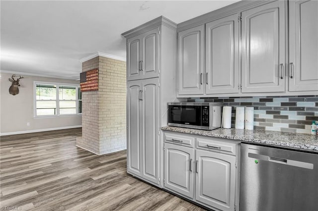 kitchen with gray cabinetry, crown molding, tasteful backsplash, light stone counters, and stainless steel appliances