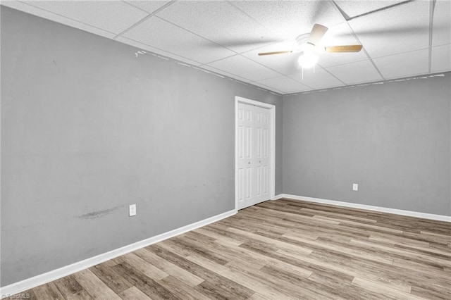 empty room with a paneled ceiling, ceiling fan, and light hardwood / wood-style floors