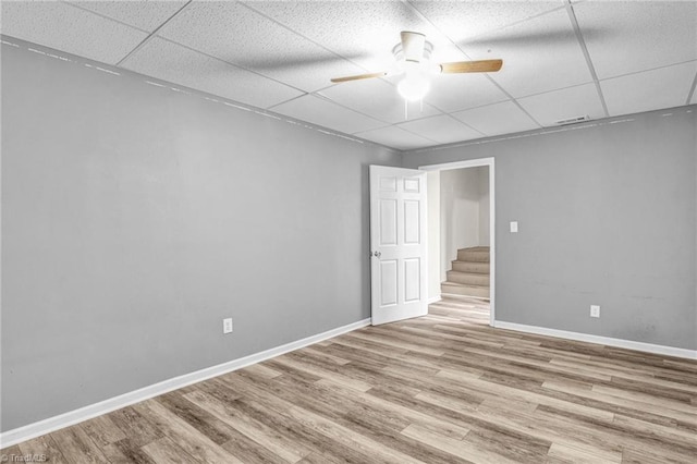 spare room featuring a paneled ceiling, ceiling fan, and light wood-type flooring