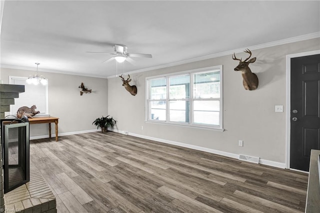 living room featuring wood-type flooring, ceiling fan with notable chandelier, and crown molding