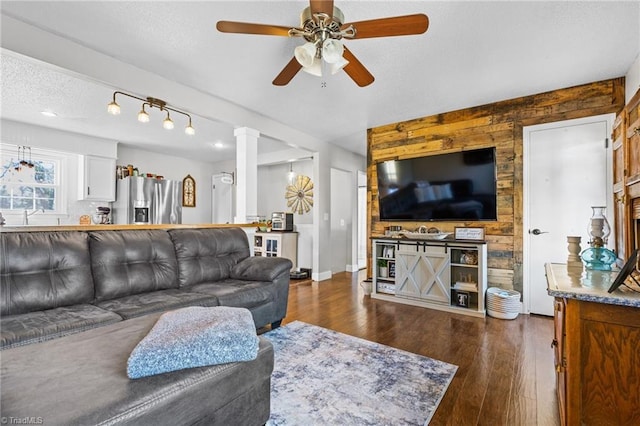 living room with ceiling fan, dark wood-type flooring, and a textured ceiling