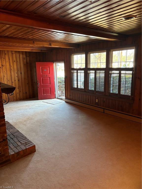 carpeted entrance foyer featuring beamed ceiling, wooden walls, and a baseboard radiator