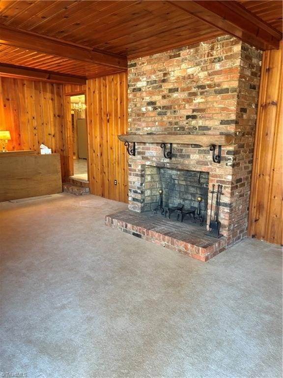 unfurnished living room with a fireplace, wooden ceiling, wooden walls, and beam ceiling