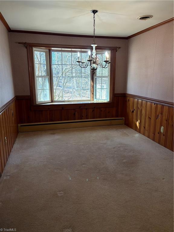 unfurnished dining area featuring crown molding, plenty of natural light, carpet floors, and a baseboard heating unit