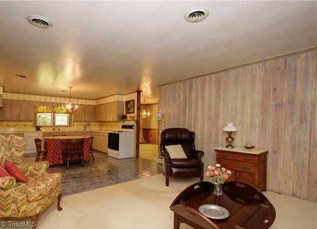 living room featuring a chandelier and wood walls