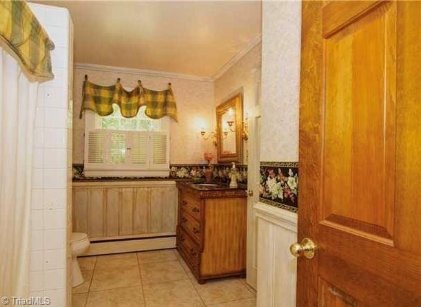 interior space featuring baseboard heating, light tile patterned flooring, and ornamental molding