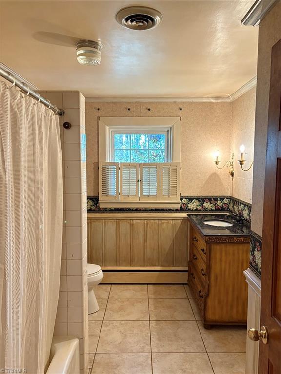 full bathroom featuring a baseboard heating unit, tile patterned floors, crown molding, and toilet