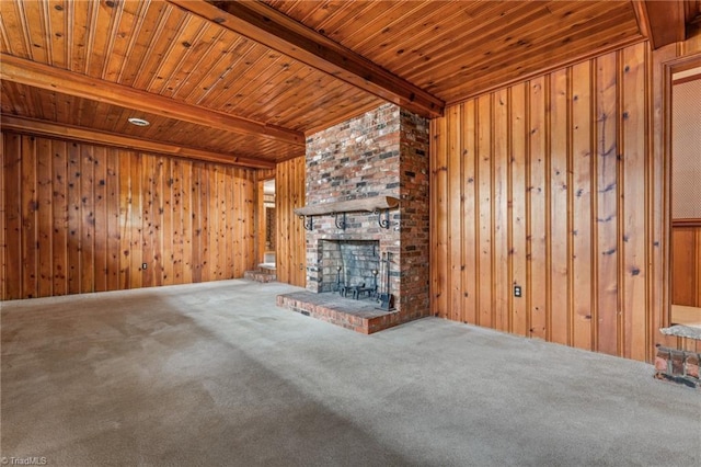 unfurnished living room featuring carpet, wood ceiling, beamed ceiling, a fireplace, and wood walls