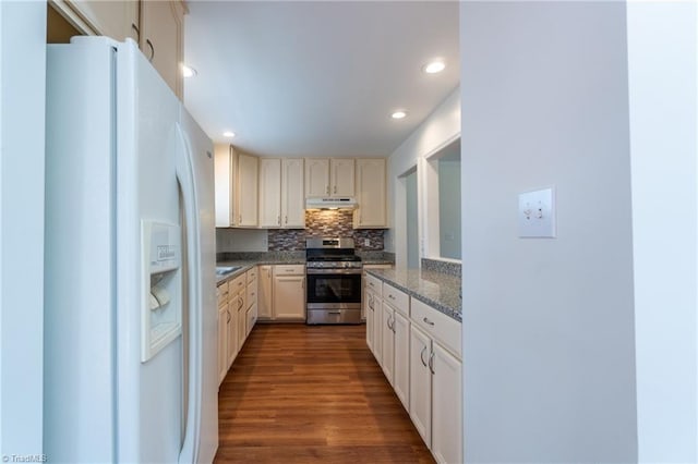 kitchen featuring dark stone counters, stainless steel stove, tasteful backsplash, white refrigerator with ice dispenser, and hardwood / wood-style flooring