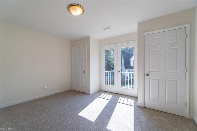 interior space with a closet, access to exterior, light colored carpet, and french doors