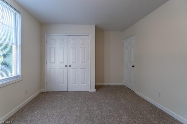 unfurnished bedroom with multiple windows, a closet, and carpet floors