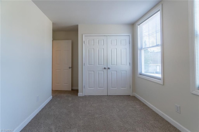 unfurnished bedroom with carpet, a closet, and multiple windows