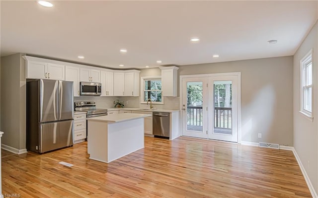 kitchen with plenty of natural light, a center island, white cabinets, and appliances with stainless steel finishes