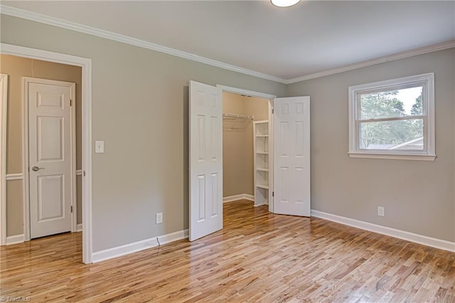 unfurnished bedroom with ornamental molding, a spacious closet, and light hardwood / wood-style floors