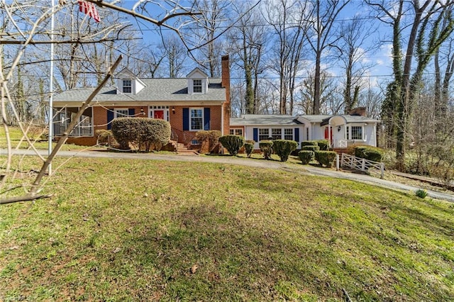 new england style home with crawl space, brick siding, a chimney, and a front lawn