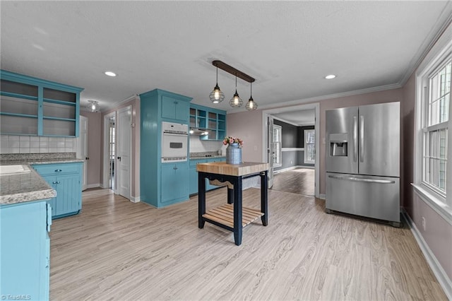 kitchen with tasteful backsplash, white oven, stainless steel fridge, and blue cabinetry