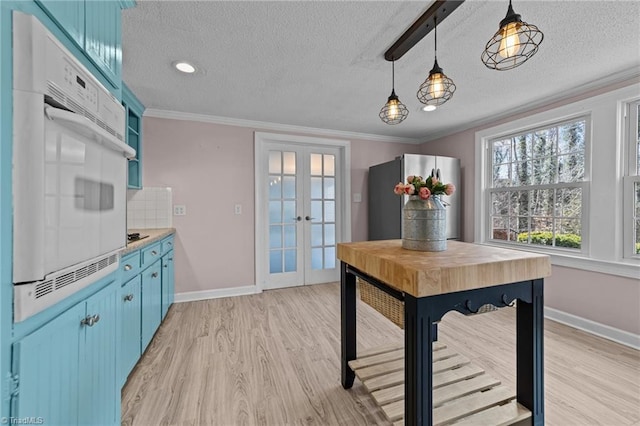 interior space featuring light wood-style floors, baseboards, crown molding, and french doors