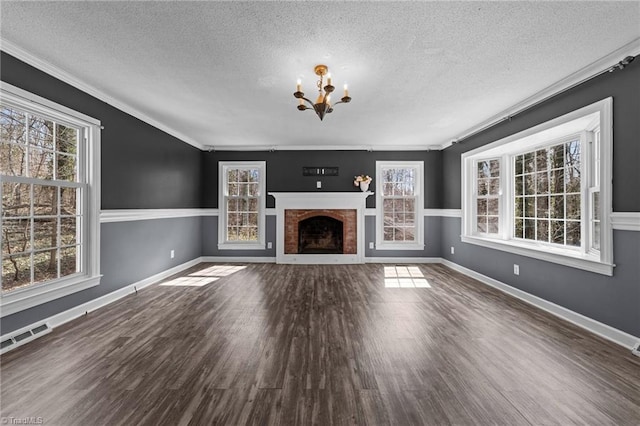 unfurnished living room featuring a textured ceiling, a fireplace, wood finished floors, visible vents, and an inviting chandelier