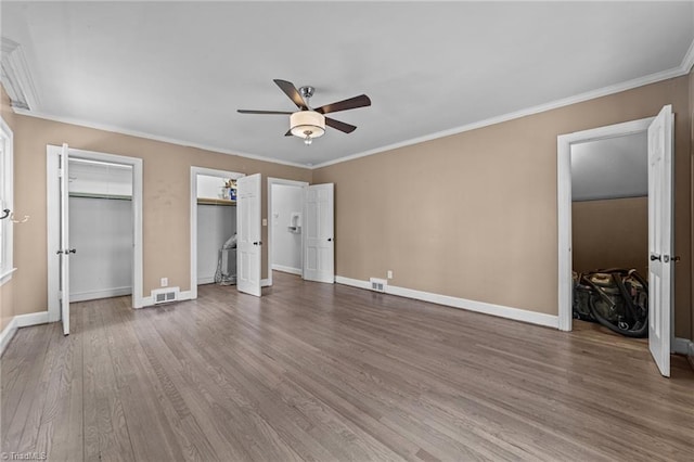 unfurnished bedroom featuring baseboards, crown molding, visible vents, and wood finished floors