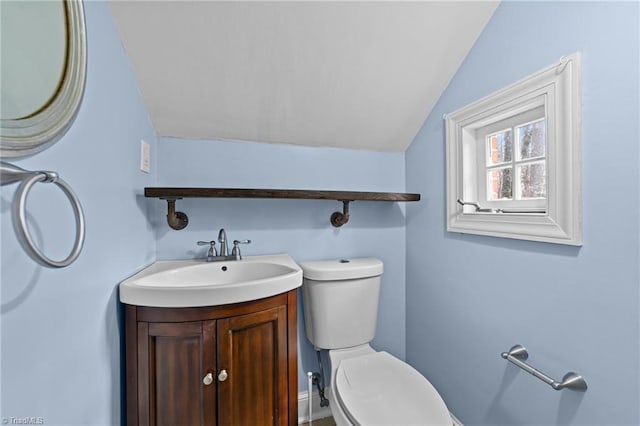 bathroom with vaulted ceiling, vanity, and toilet