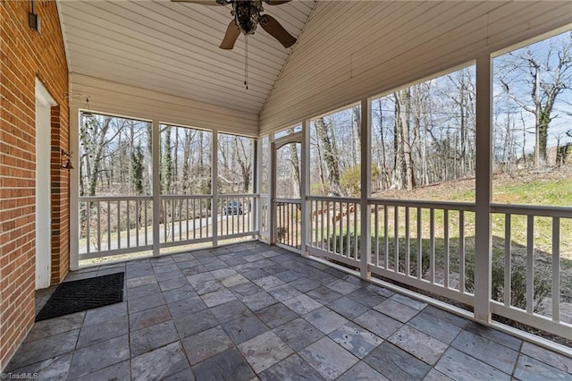 unfurnished sunroom featuring lofted ceiling, a ceiling fan, and a wealth of natural light