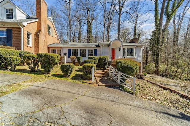 view of front of property featuring brick siding and a chimney