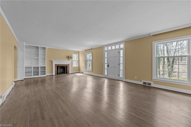 unfurnished living room featuring ornamental molding, arched walkways, a brick fireplace, and visible vents