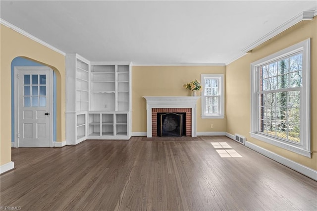 unfurnished living room featuring arched walkways, wood finished floors, visible vents, and crown molding