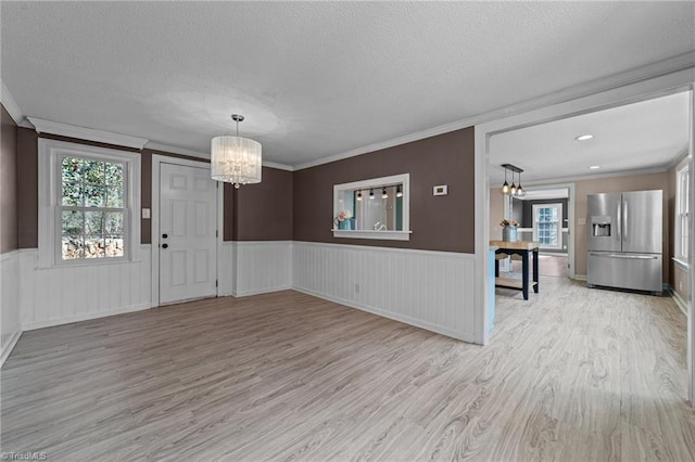 interior space with wainscoting, a textured ceiling, wood finished floors, a chandelier, and plenty of natural light