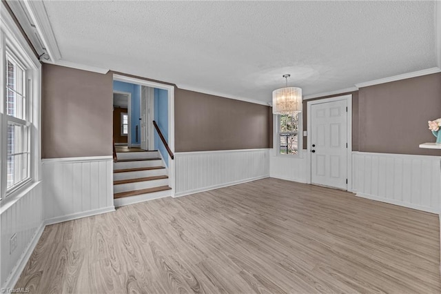 unfurnished room featuring a wainscoted wall, a textured ceiling, an inviting chandelier, and wood finished floors