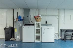 clothes washing area with washer and dryer, water heater, and laundry area