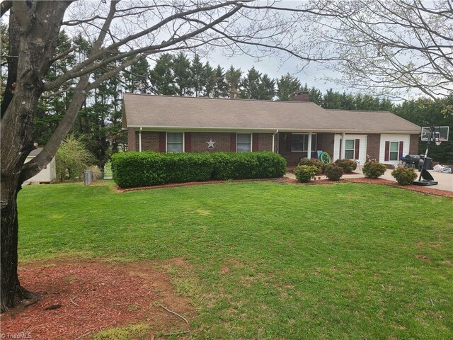 ranch-style house featuring brick siding, a front lawn, and a chimney