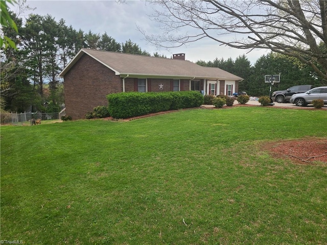 ranch-style house featuring fence, brick siding, a chimney, and a front lawn