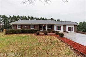 single story home featuring concrete driveway and a front lawn