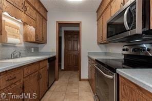 kitchen with stainless steel appliances, brown cabinets, and a sink
