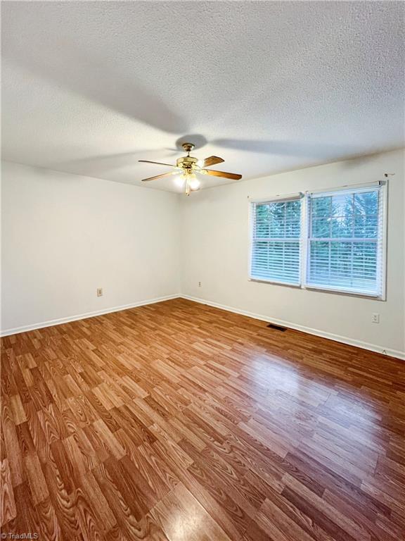 spare room with a textured ceiling, wood-type flooring, and ceiling fan