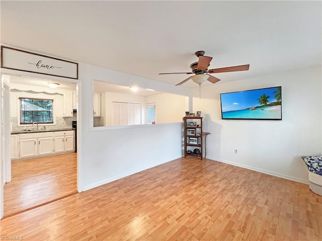 unfurnished living room featuring ceiling fan, sink, and light hardwood / wood-style flooring