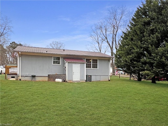 back of property with central AC and a lawn