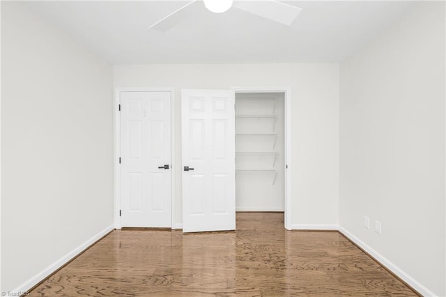 unfurnished bedroom with hardwood / wood-style floors, a spacious closet, a closet, and ceiling fan