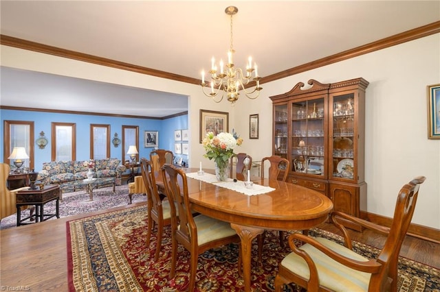 dining room featuring ornamental molding, plenty of natural light, wood-type flooring, and an inviting chandelier