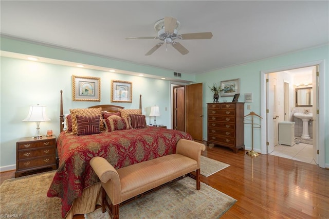 bedroom with ensuite bathroom, sink, ceiling fan, and light hardwood / wood-style floors