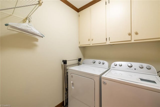 washroom featuring ornamental molding, washing machine and dryer, and cabinets