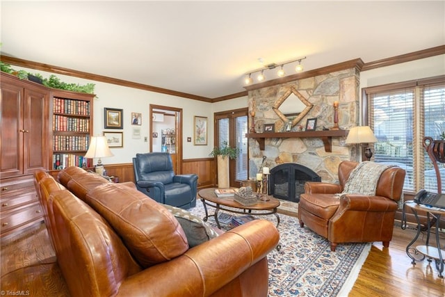 living room with hardwood / wood-style flooring, track lighting, a healthy amount of sunlight, and a stone fireplace